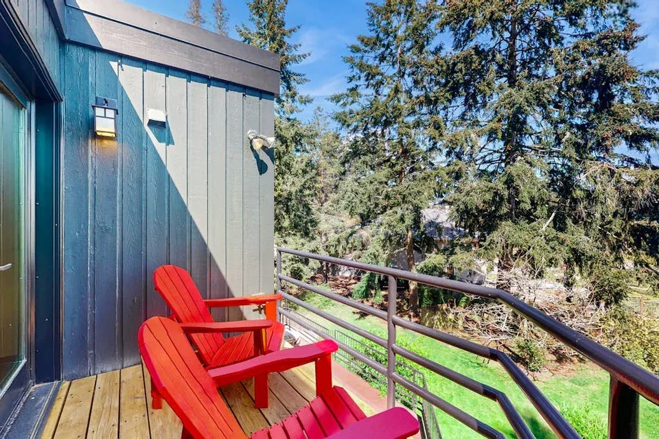 A wooden deck with red seating overlooks a leafy outdoor area.