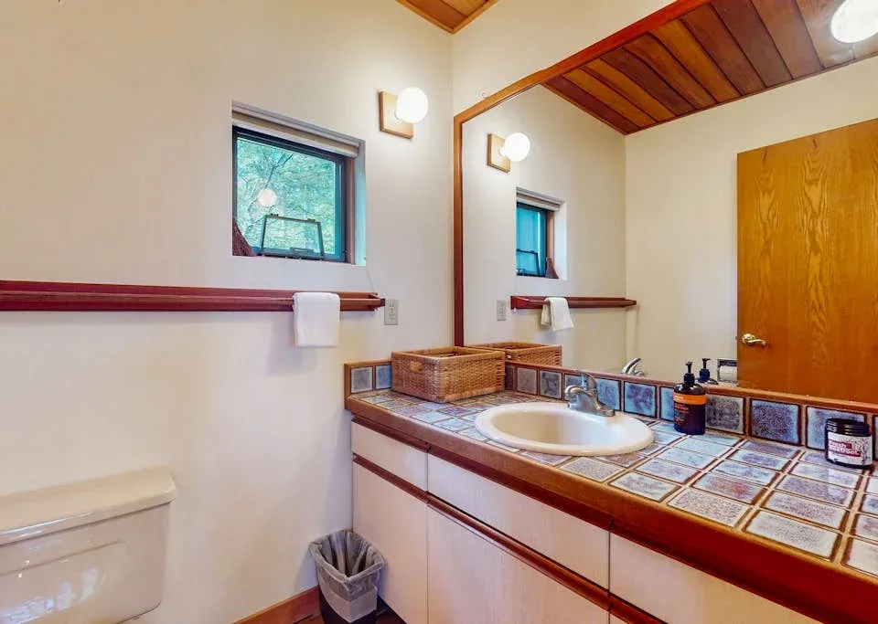 A bathroom vanity with a sink, tiled counter, and large mirror.