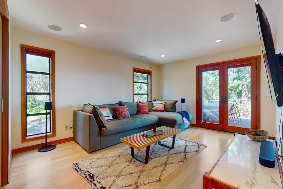 A bright living room features a sectional sofa and large glass doors opening to a patio.