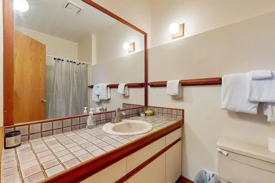 A bathroom vanity with a tiled counter and a mirror.