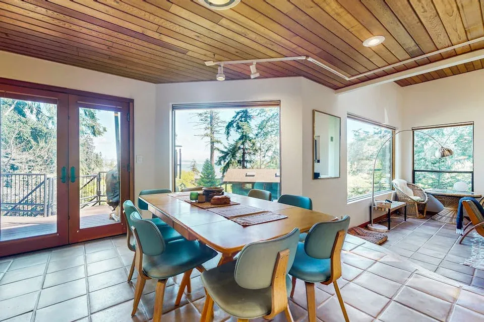 A dining area with a wooden table and chairs beneath a wood-paneled ceiling.
