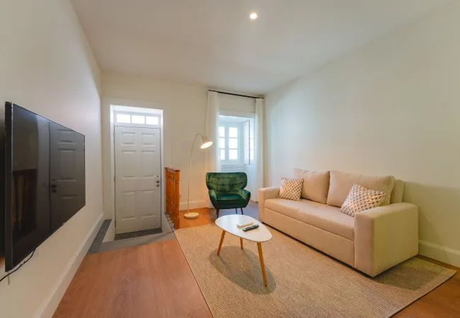 Una sala de estar con un sofá beige y una mesa de centro pequeña.