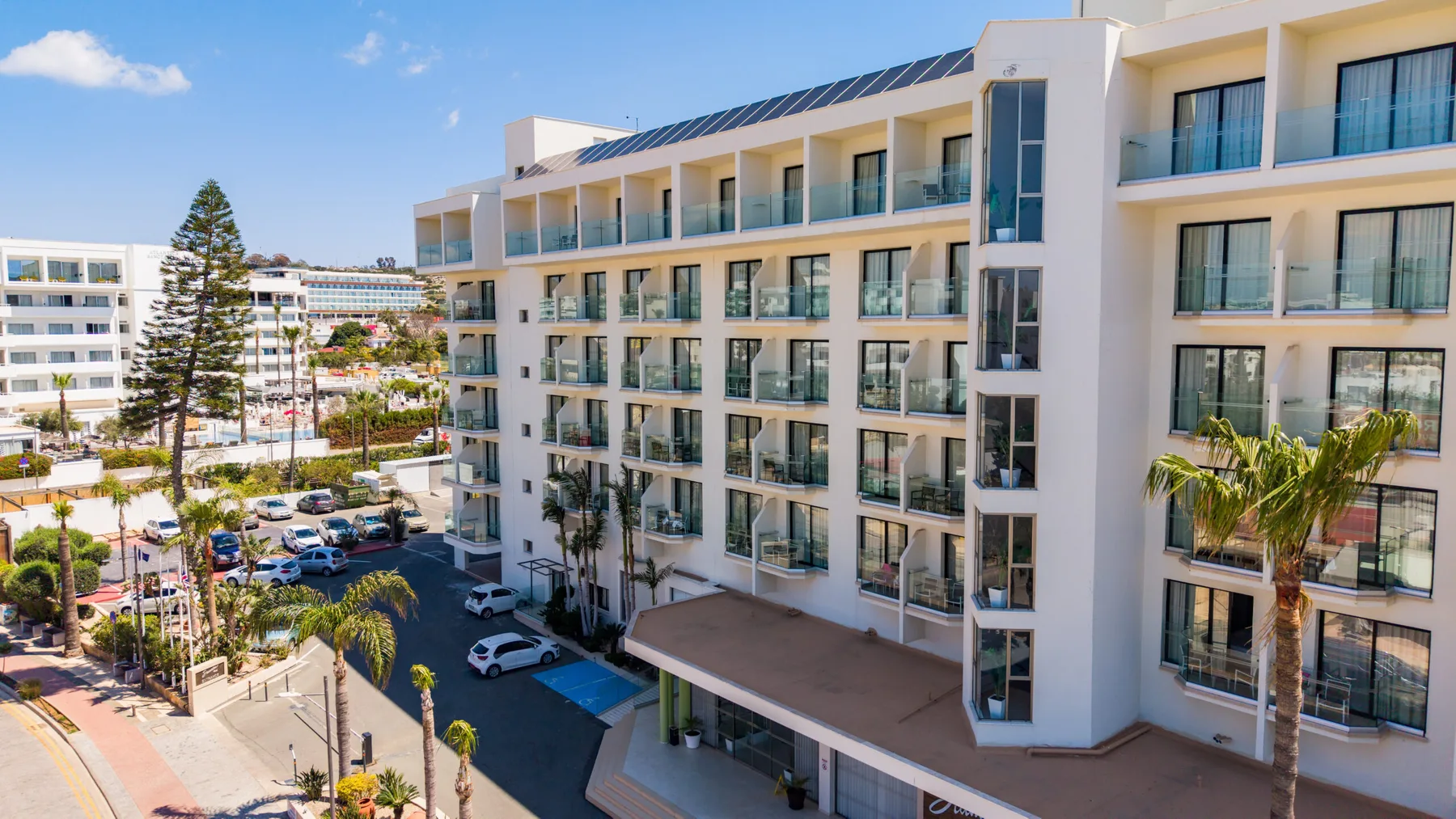 Representative hotel space: Modern hotel buildings line a landscaped street with parked cars.