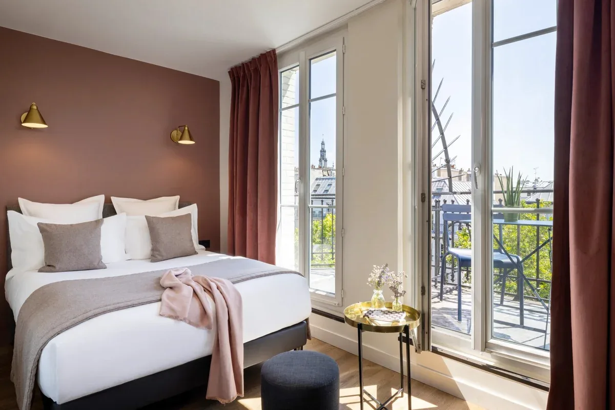 Espacio representativo del hotel: Dormitorio con una cama junto a ventanas altas que dan a un balcón.