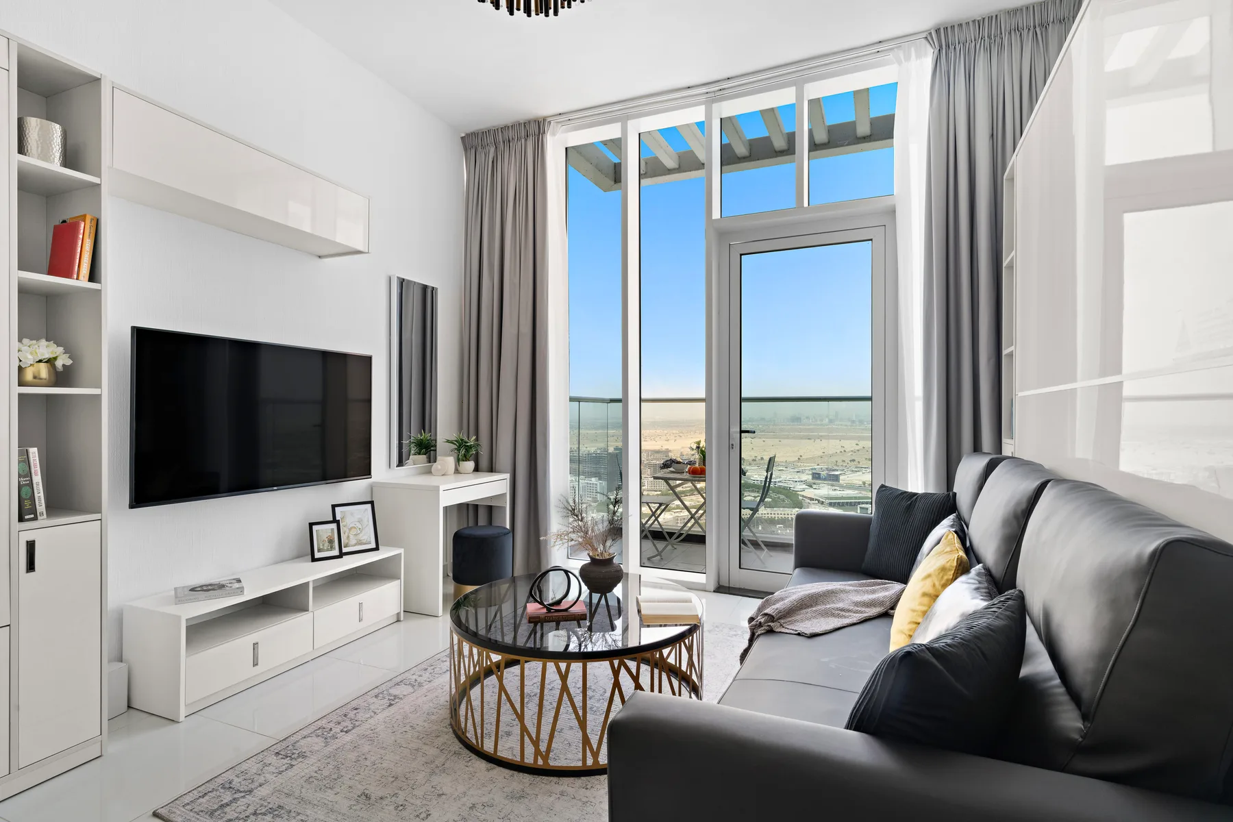 Una sala luminosa tiene un televisor, asientos y grandes ventanas con vistas al paisaje.