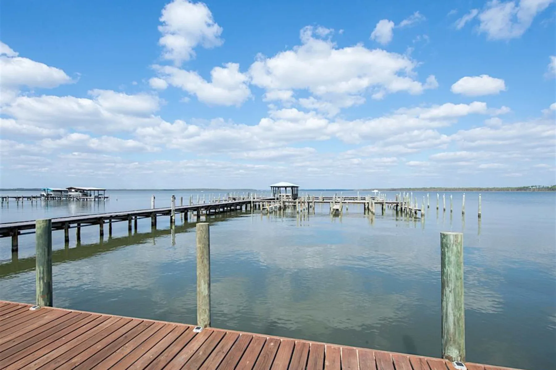 Zona común: Un muelle de madera se extiende sobre aguas tranquilas bajo un cielo parcialmente nublado.