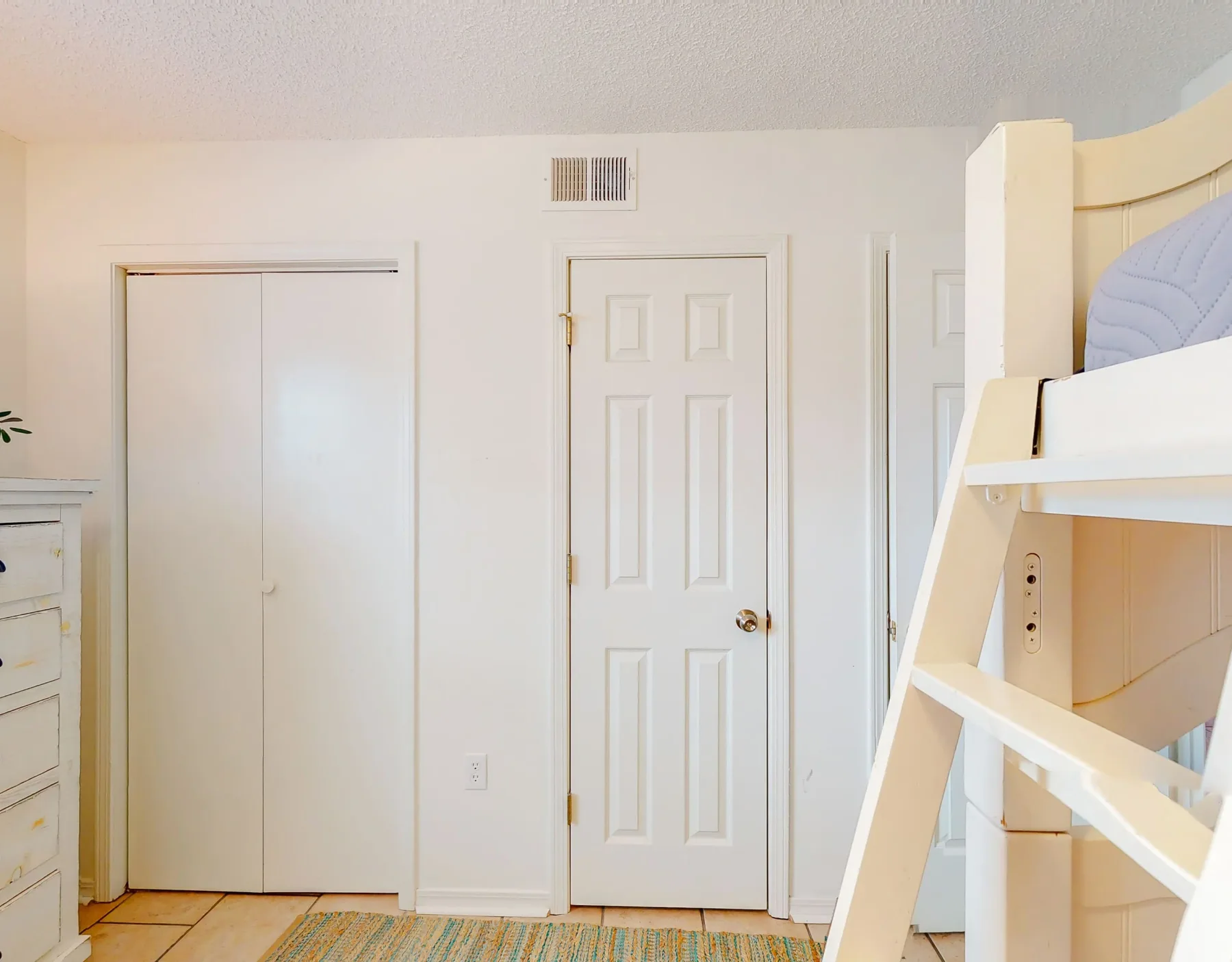 Un dormitorio luminoso con una litera blanca y puertas cerradas.