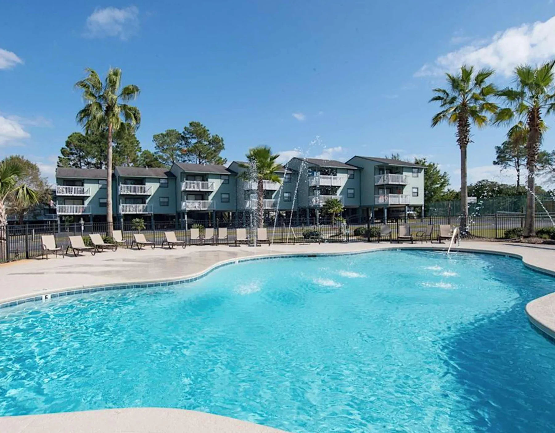 Zona común: Una piscina al aire libre con edificios de apartamentos y palmeras al fondo.