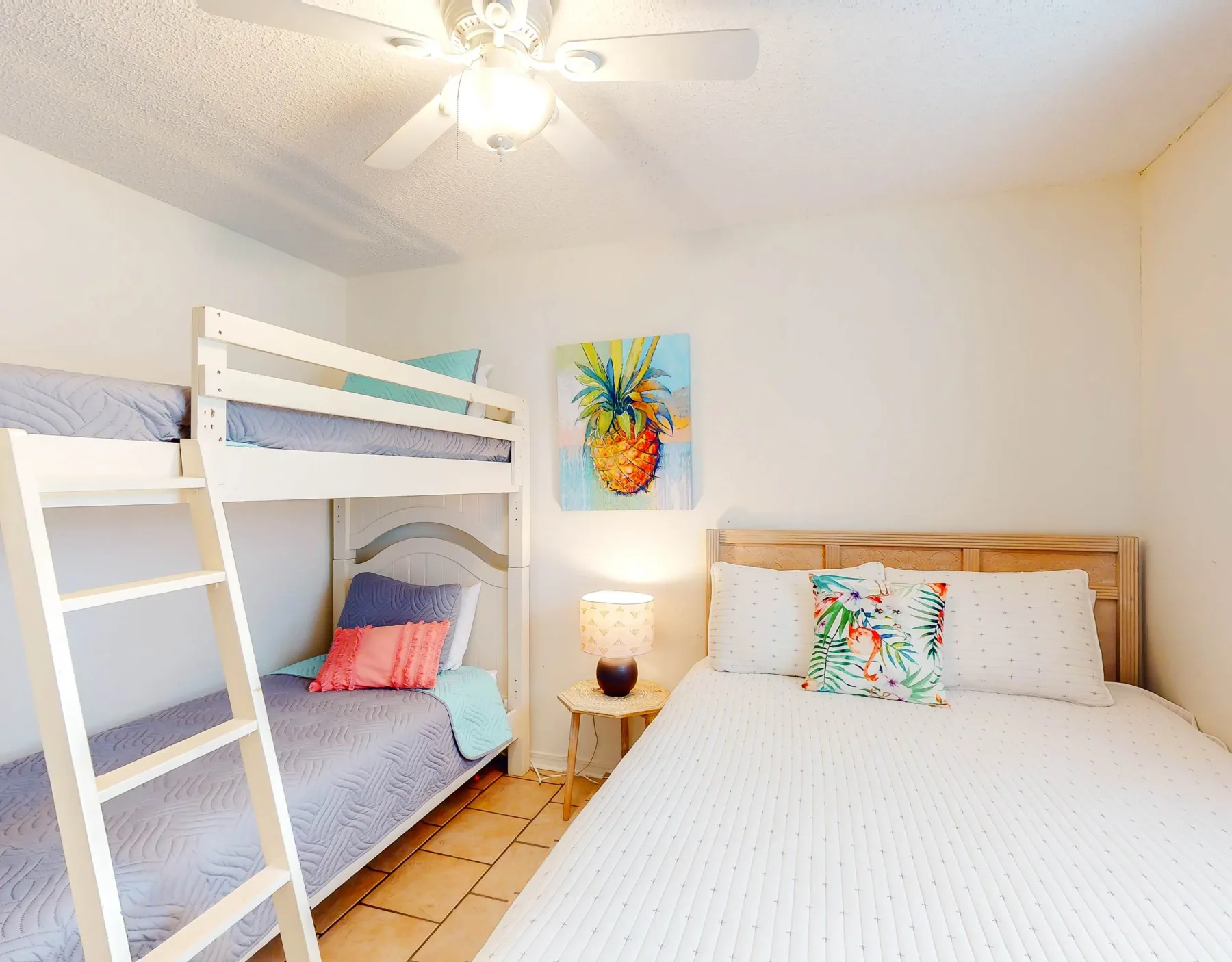 Un dormitorio luminoso con una cama de madera, literas blancas y arte colorido en la pared.
