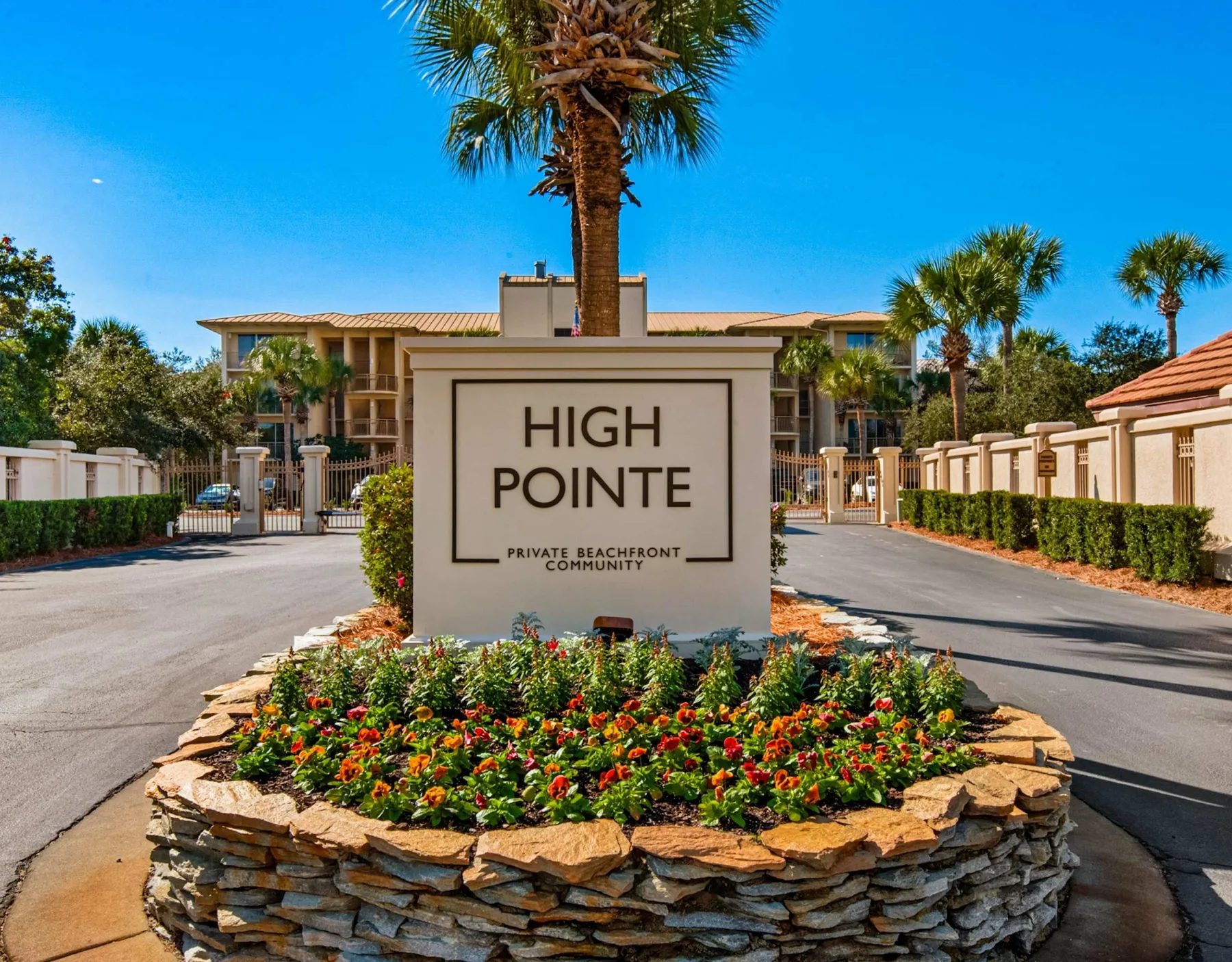 Shared amenity: A landscaped entrance features a sign in front of low-rise buildings and palm trees.