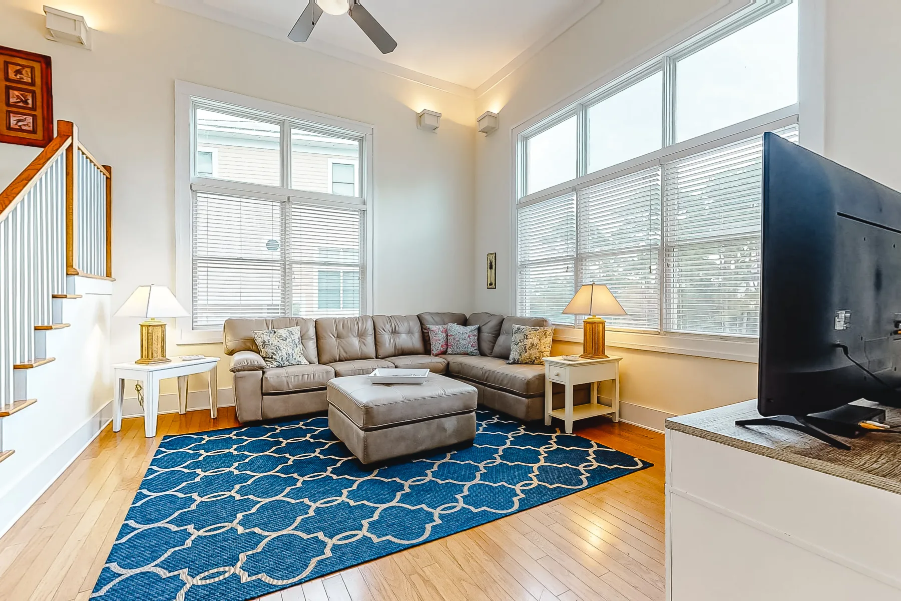 A bright living room with a sectional seating area, rug, and large windows.