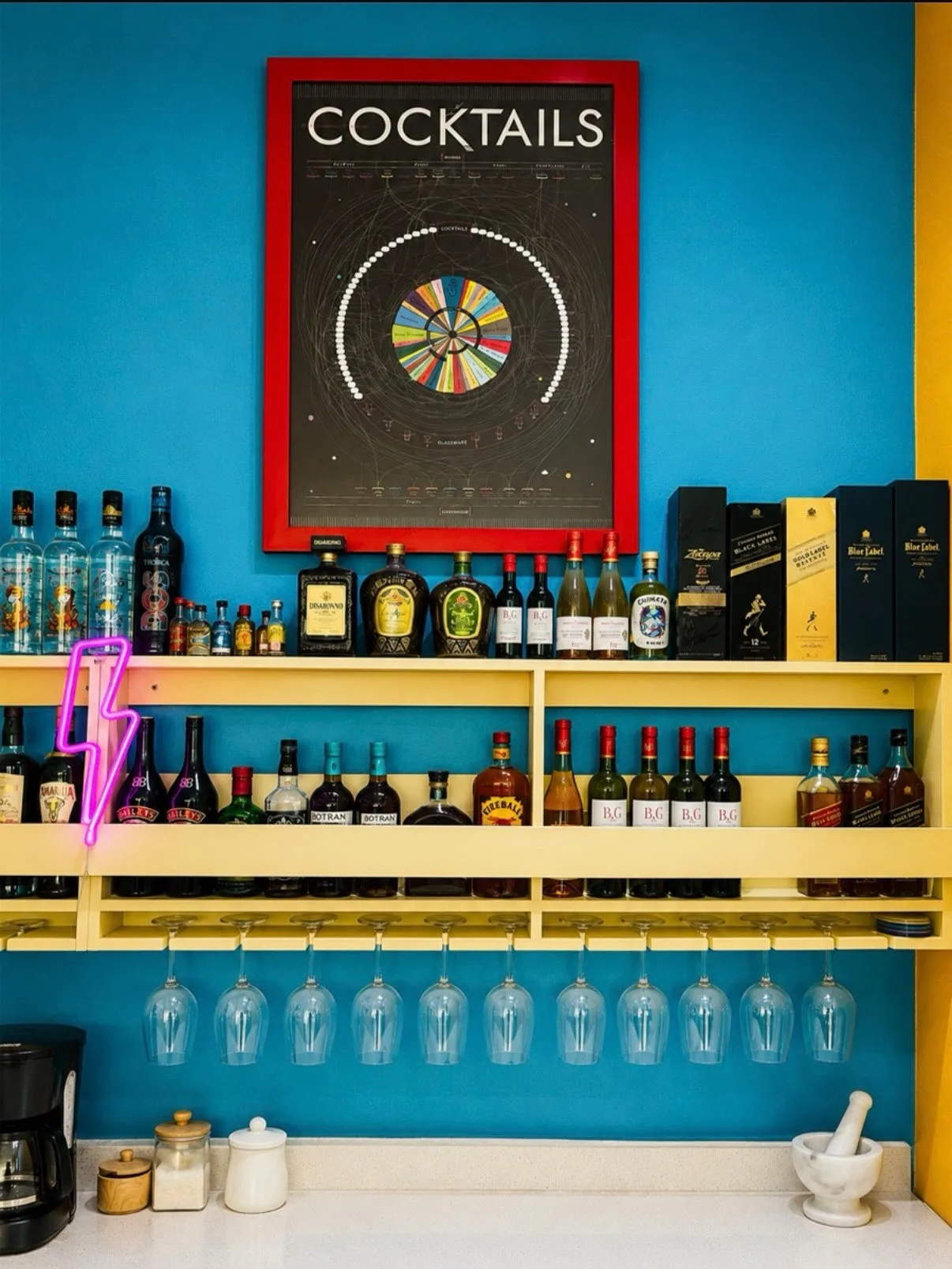Espacio representativo del hotel: Una colorida zona de bar muestra botellas y copas colgantes sobre una pared azul brillante.