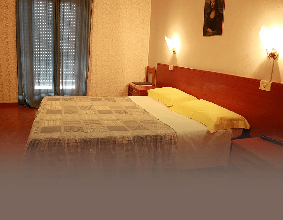 Representative hotel space: A bedroom with a bed, yellow pillows, and a curtained window.
