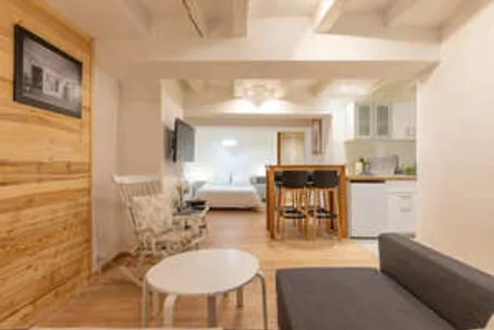 Una luminosa sala de estar de concepto abierto con mesa de comedor y cocina compacta.