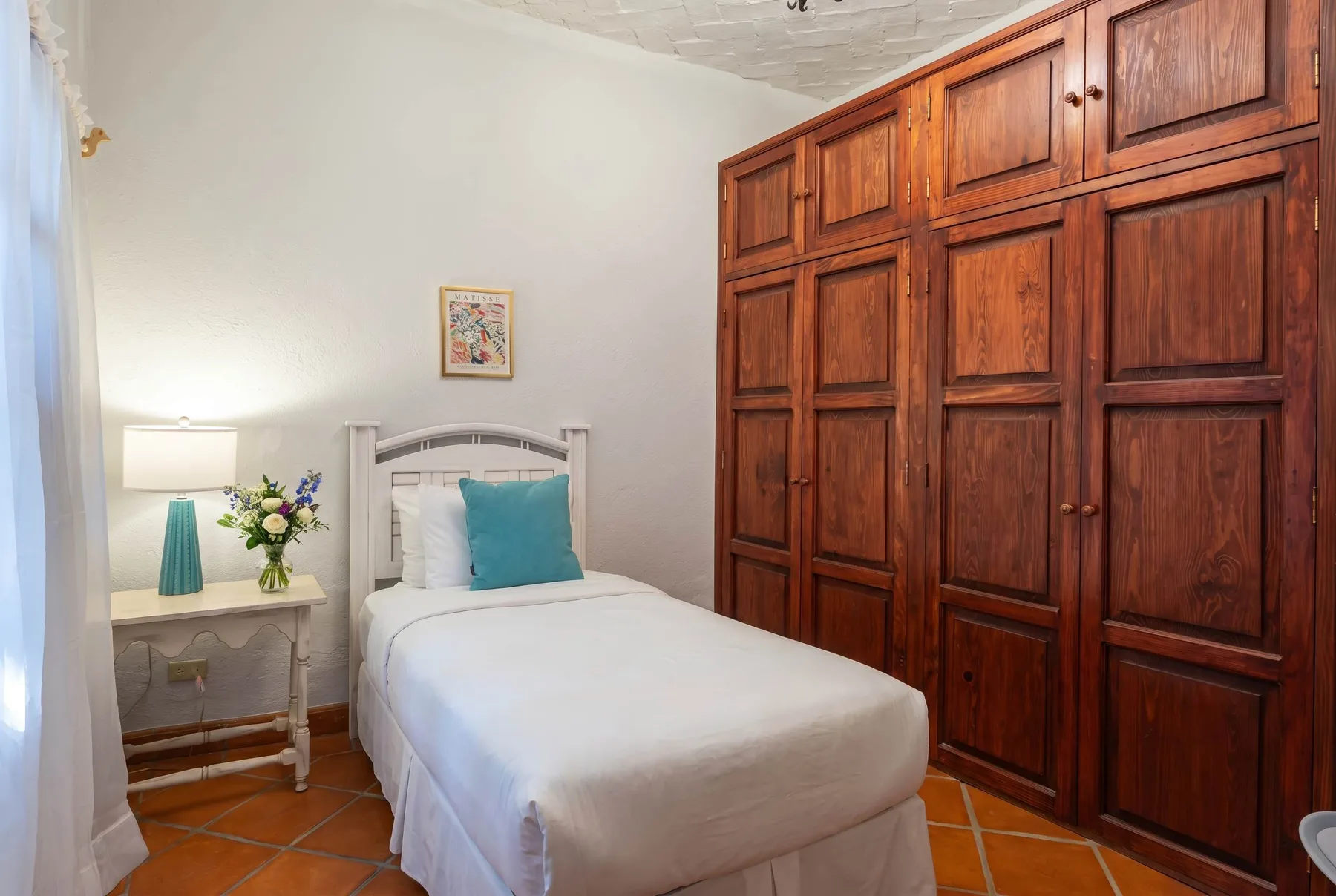 A bedroom with a single bed beside a large wooden wardrobe.