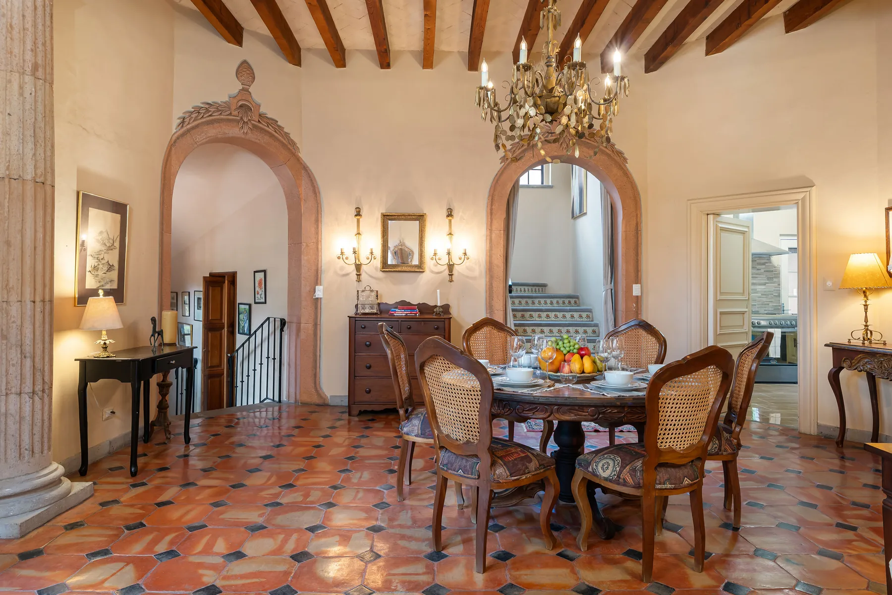 A dining room with a wooden table, carved chairs, and a chandelier.