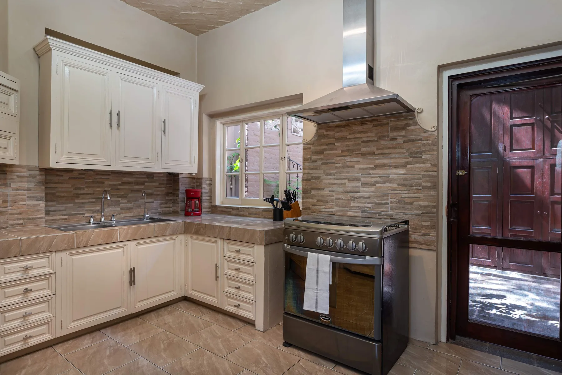 A kitchen with white cabinets, a stove, and a window.