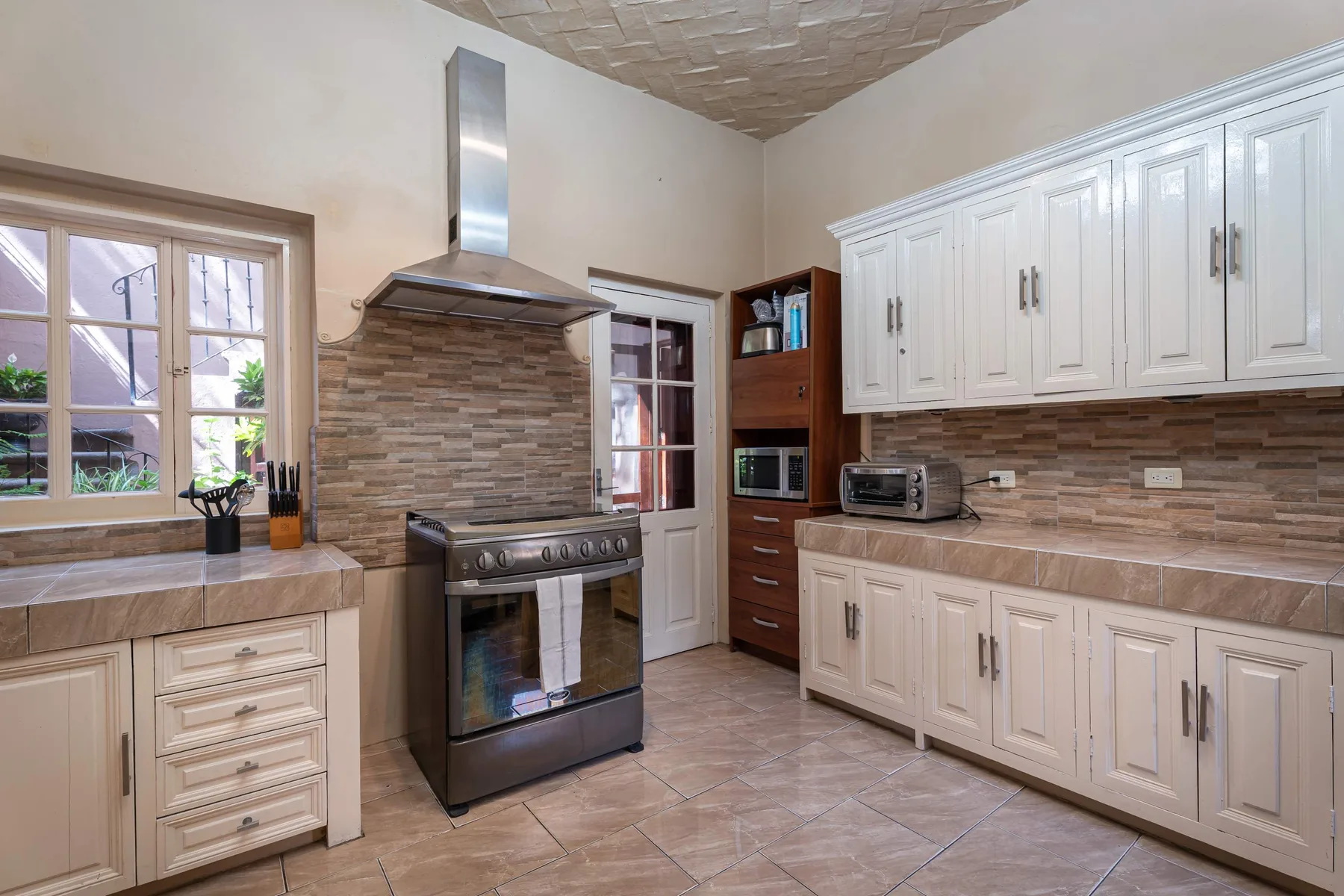 A kitchen with white cabinets, a tiled backsplash, and a freestanding range.