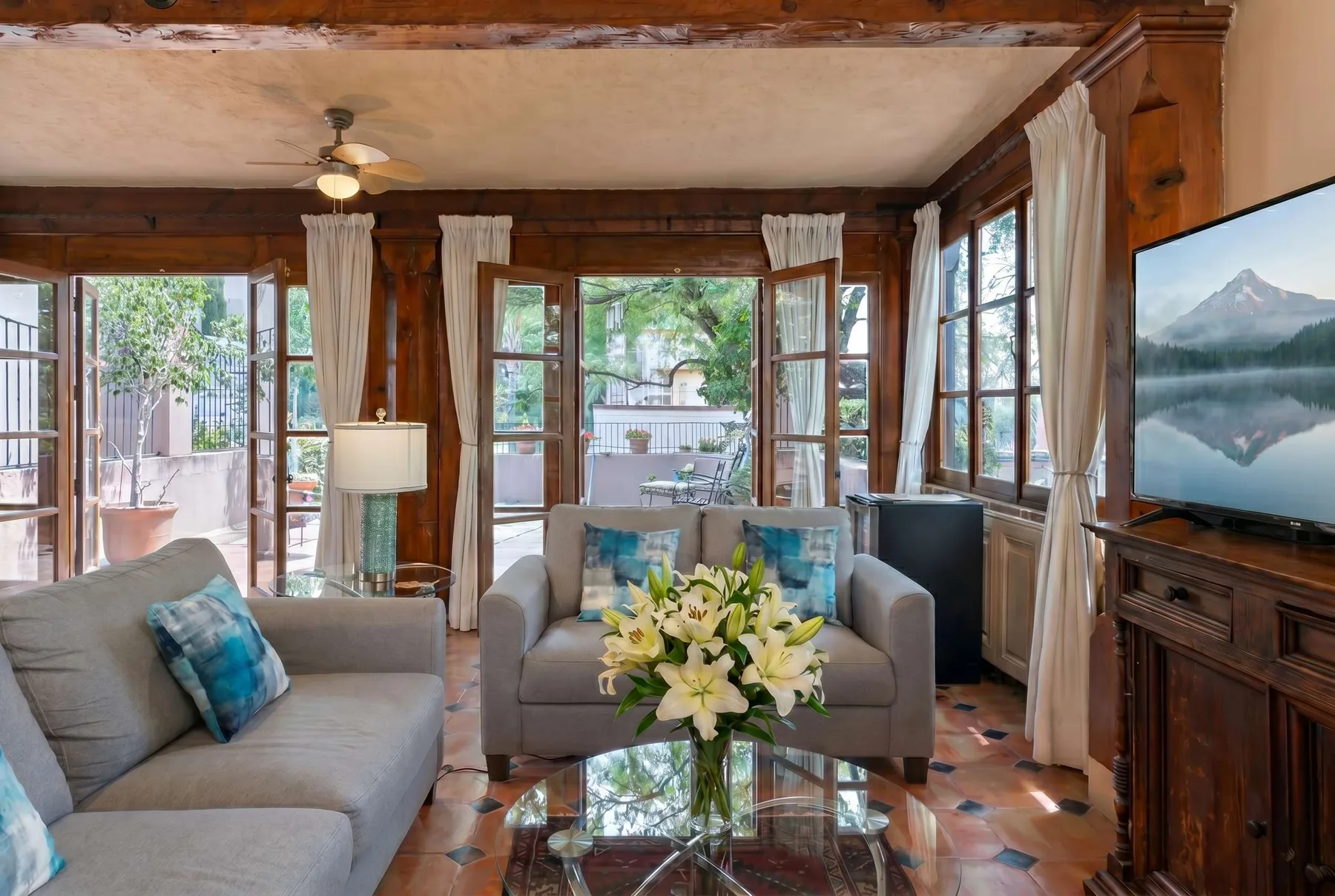 A sitting room with sofas, large windows, and a glass coffee table.