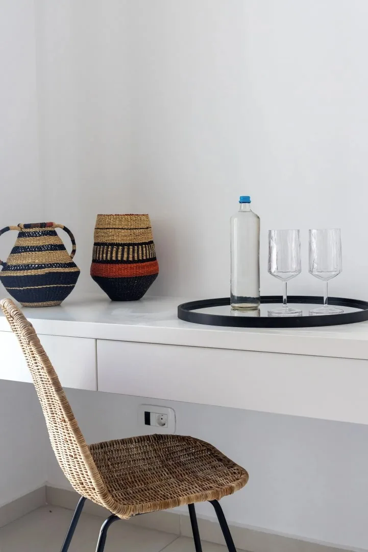 A bright dining nook with a woven chair beside a white table.