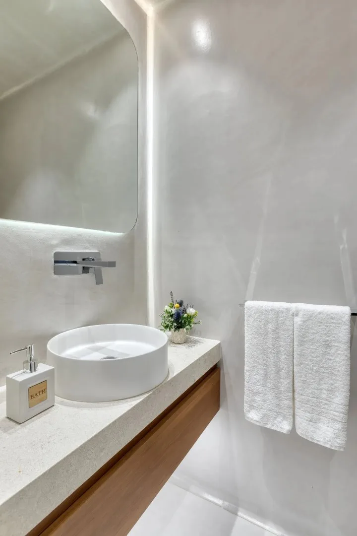 A modern bathroom vanity with a round vessel sink and folded towels.