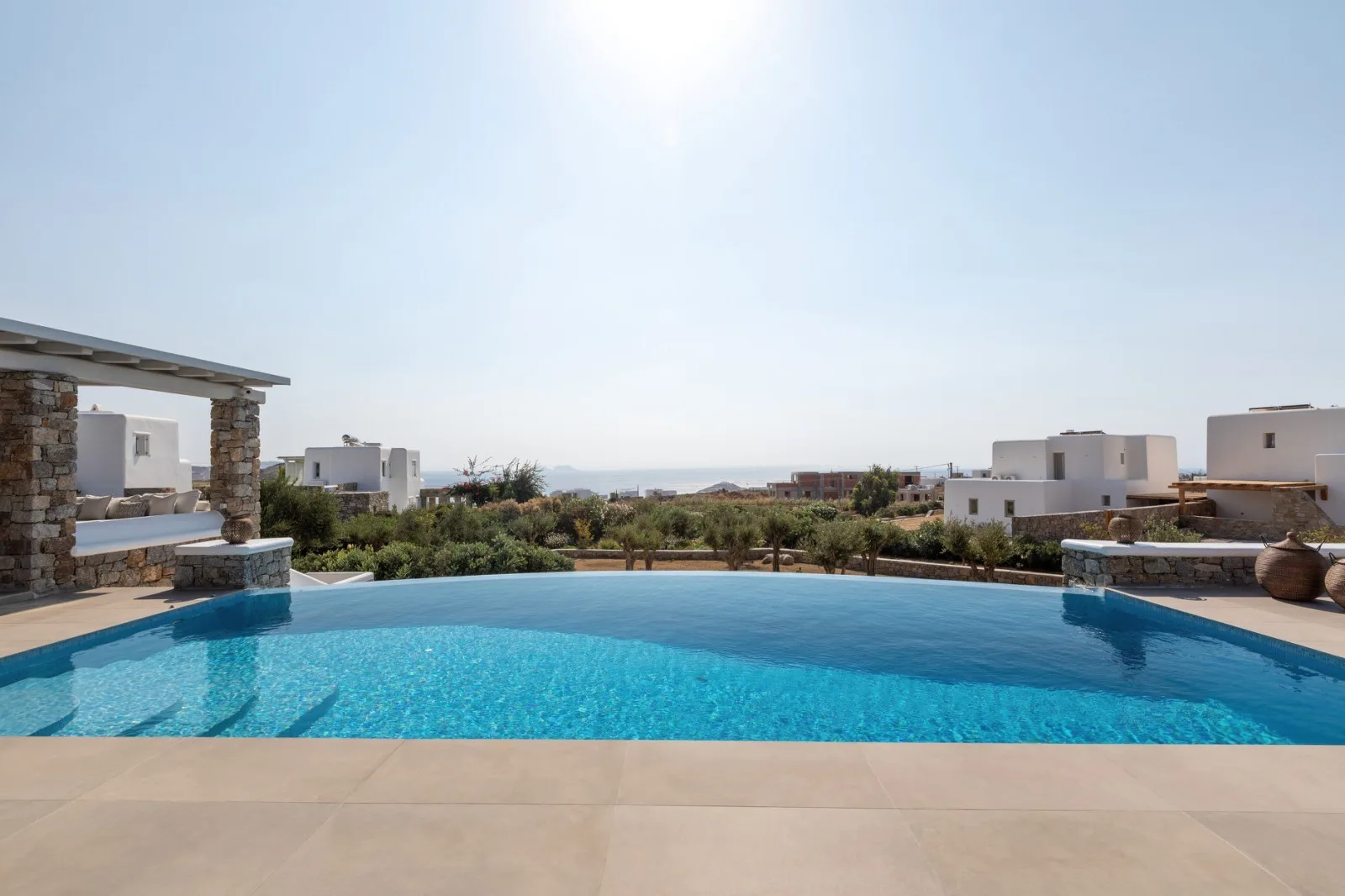 An outdoor swimming pool overlooks low buildings and a distant landscape.