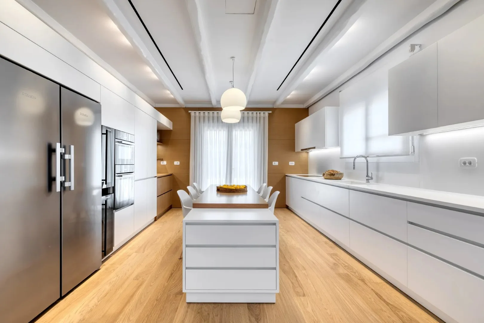 A bright modern kitchen with a central island and white cabinetry.