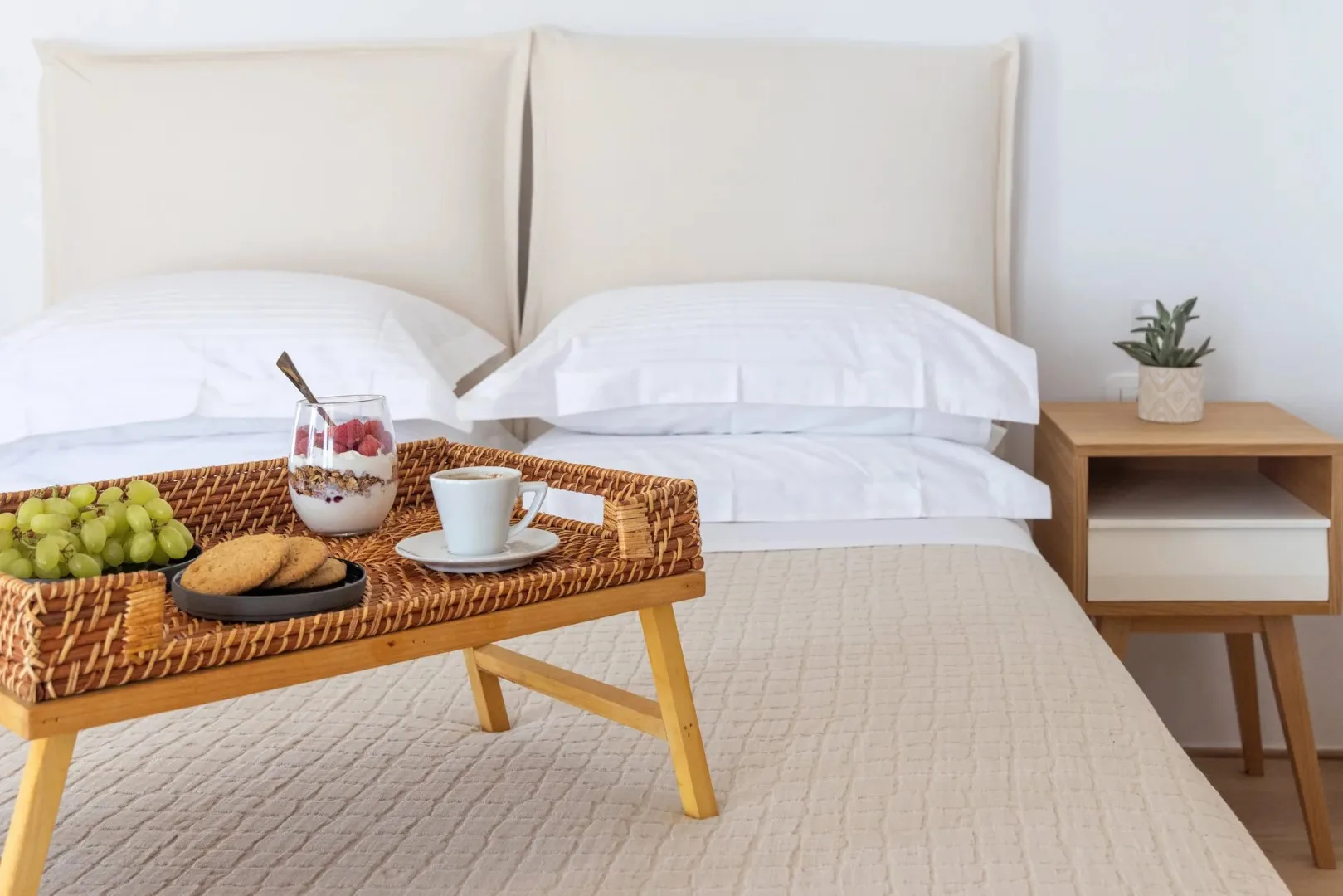 A bedroom with a neatly made bed and a breakfast tray in the foreground.