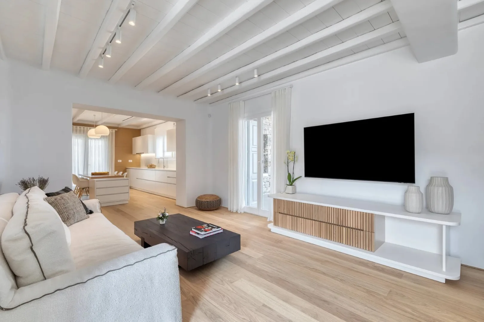 A bright living room with seating, a coffee table, and a wall-mounted television.