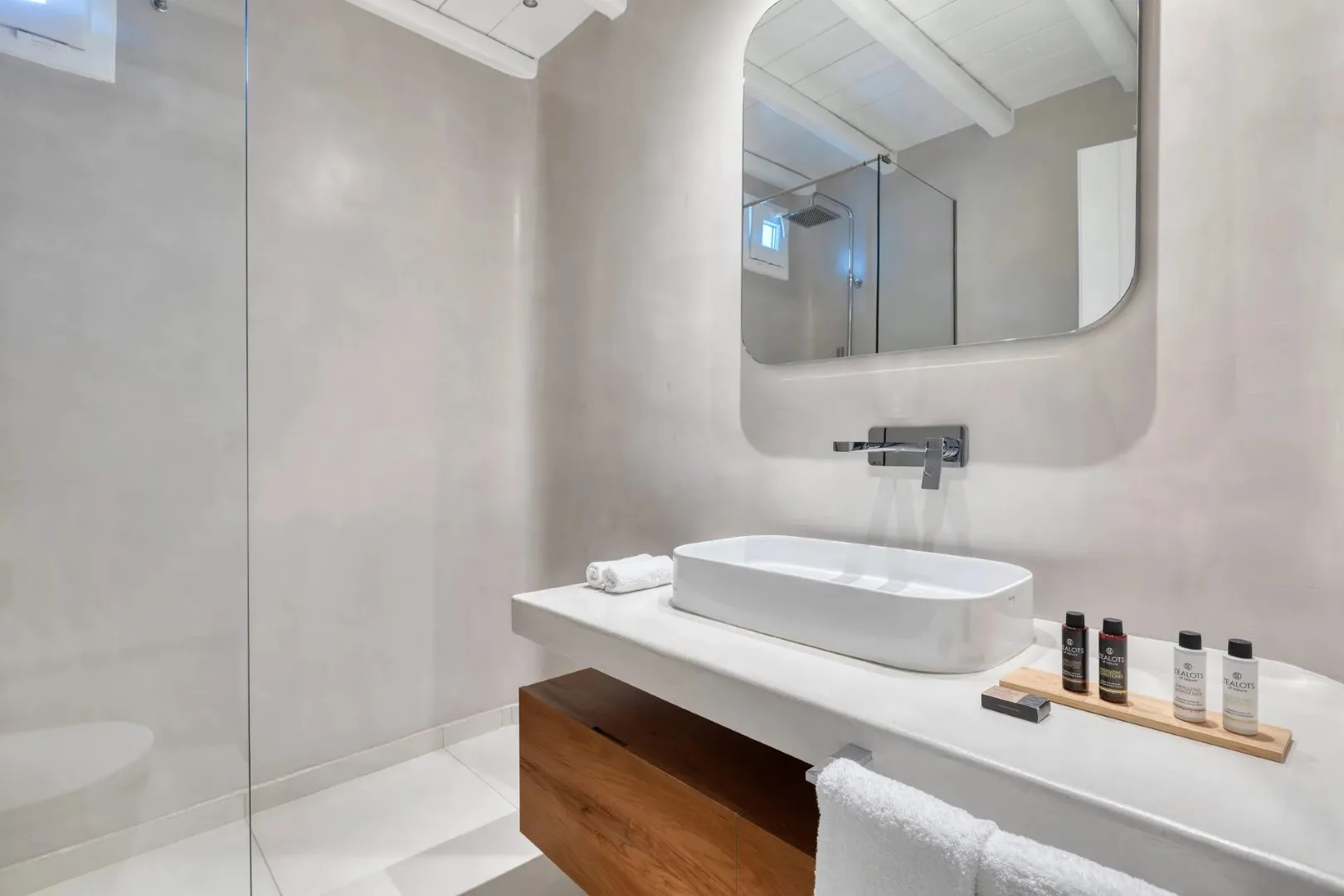 A bathroom vanity with a white basin, wall-mounted faucet, and large mirror.