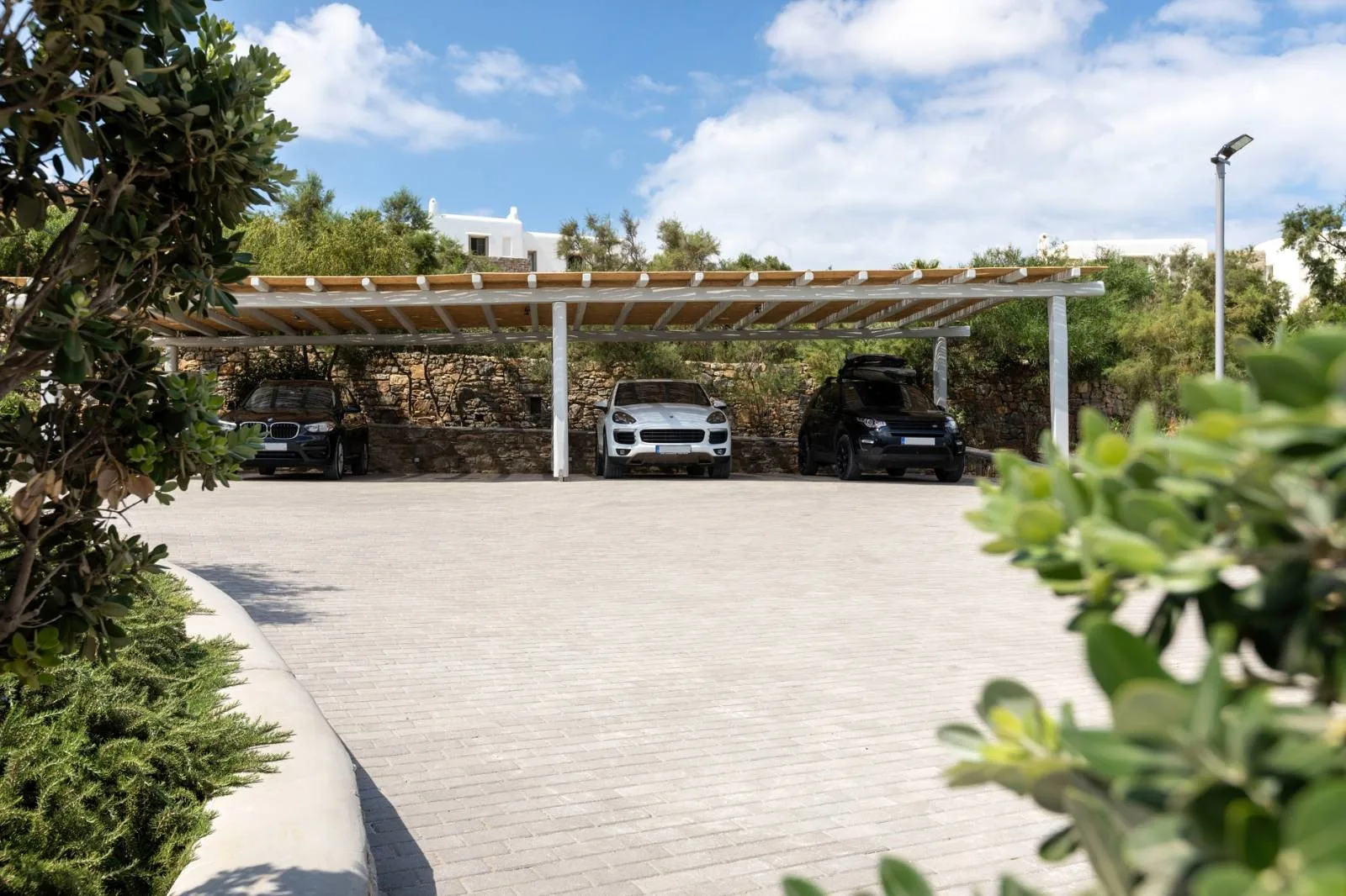 A paved parking area with several cars beneath a covered structure.