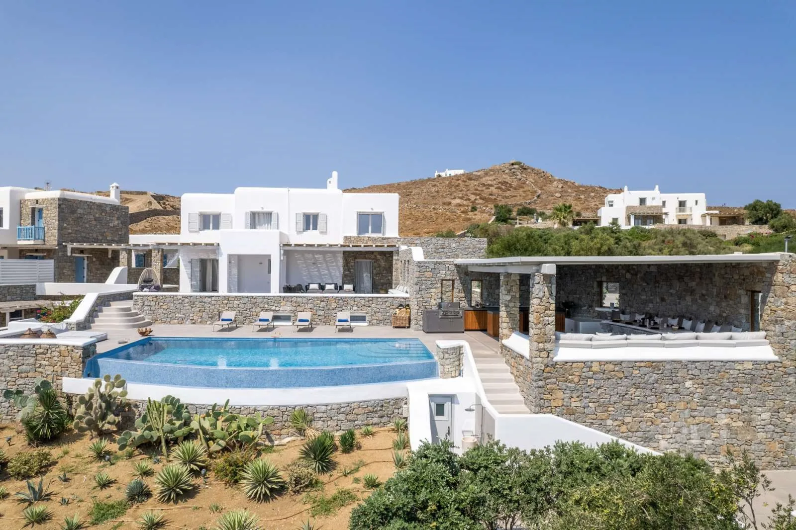 A modern villa complex overlooks a swimming pool and landscaped grounds.