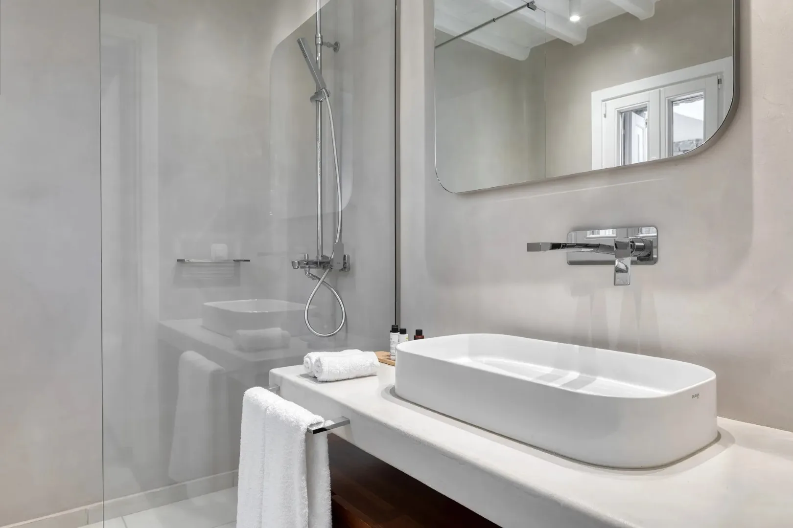 A modern bathroom with a white vessel sink and wall-mounted shower.