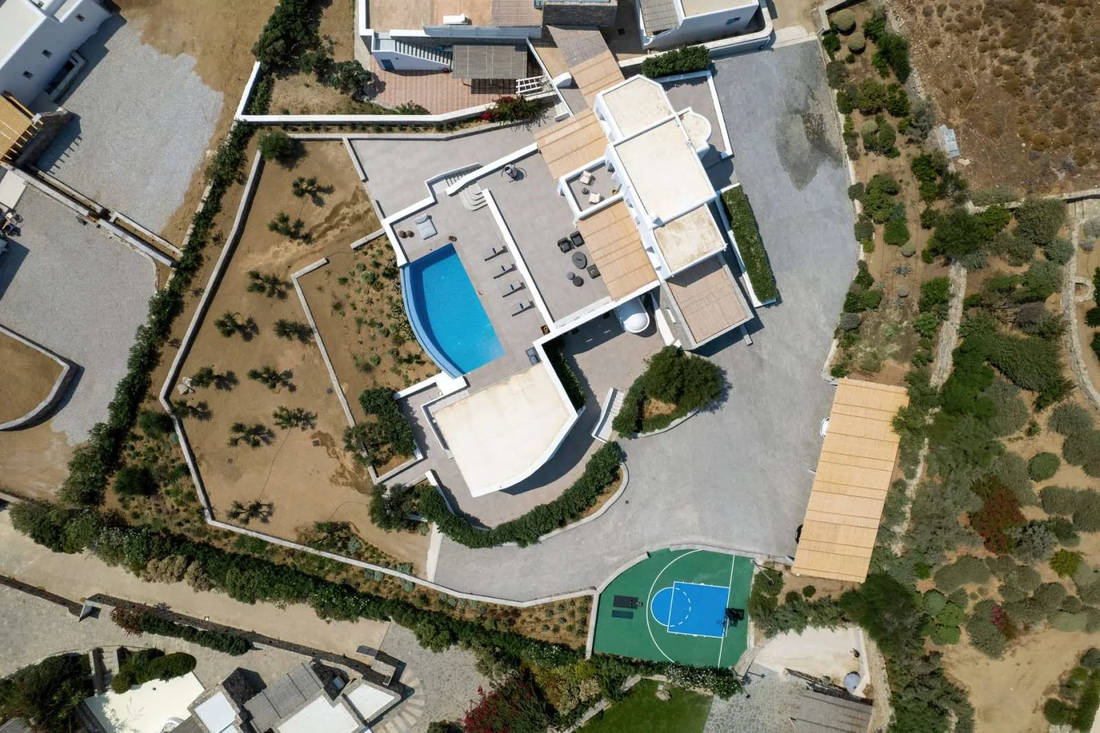 Aerial view of a residential property with a swimming pool and sports court.