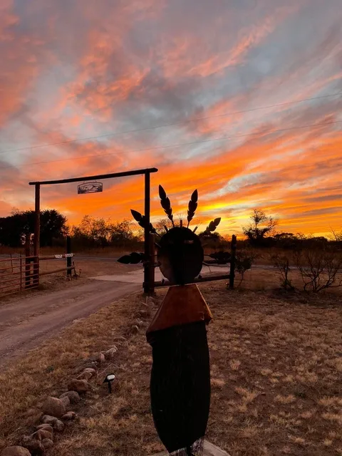 Representative hotel space: A rural driveway and gate sit beneath a vivid sunset sky.