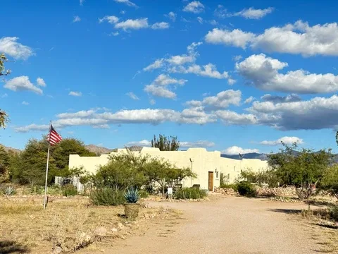 Representative hotel space: A low desert building sits beside a dirt drive under a partly cloudy sky.