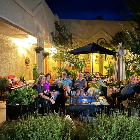 Representative hotel space: A warmly lit outdoor patio with people seated around a table beneath an umbrella.