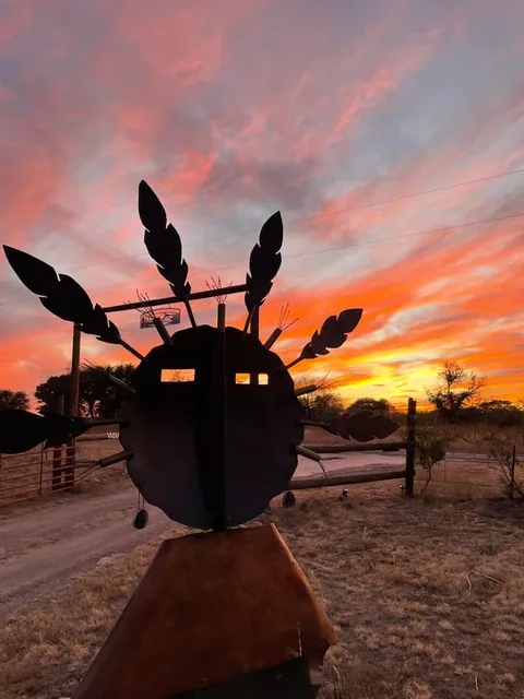 Representative hotel space: A metal sculpture stands beside a dirt road beneath a colorful sunset sky.