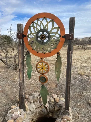 Representative hotel space: A decorative circular metal sculpture stands between wooden posts in a dry landscape.