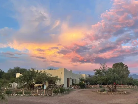 Representative hotel space: A low building and surrounding trees sit beneath a colorful sunset sky.