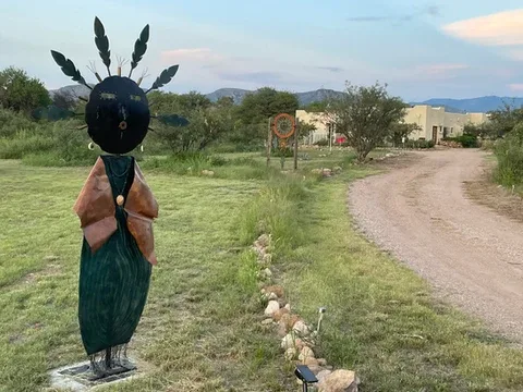Representative hotel space: A landscaped outdoor path passes a metal sculpture, with low buildings in the distance.