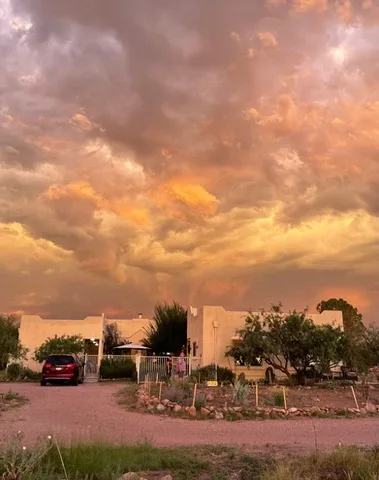Representative hotel space: A low residential building and parked car sit beneath a dramatic cloudy sky.