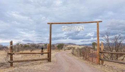 Representative hotel space: A dirt road passes through a wooden entrance gate in a dry landscape.