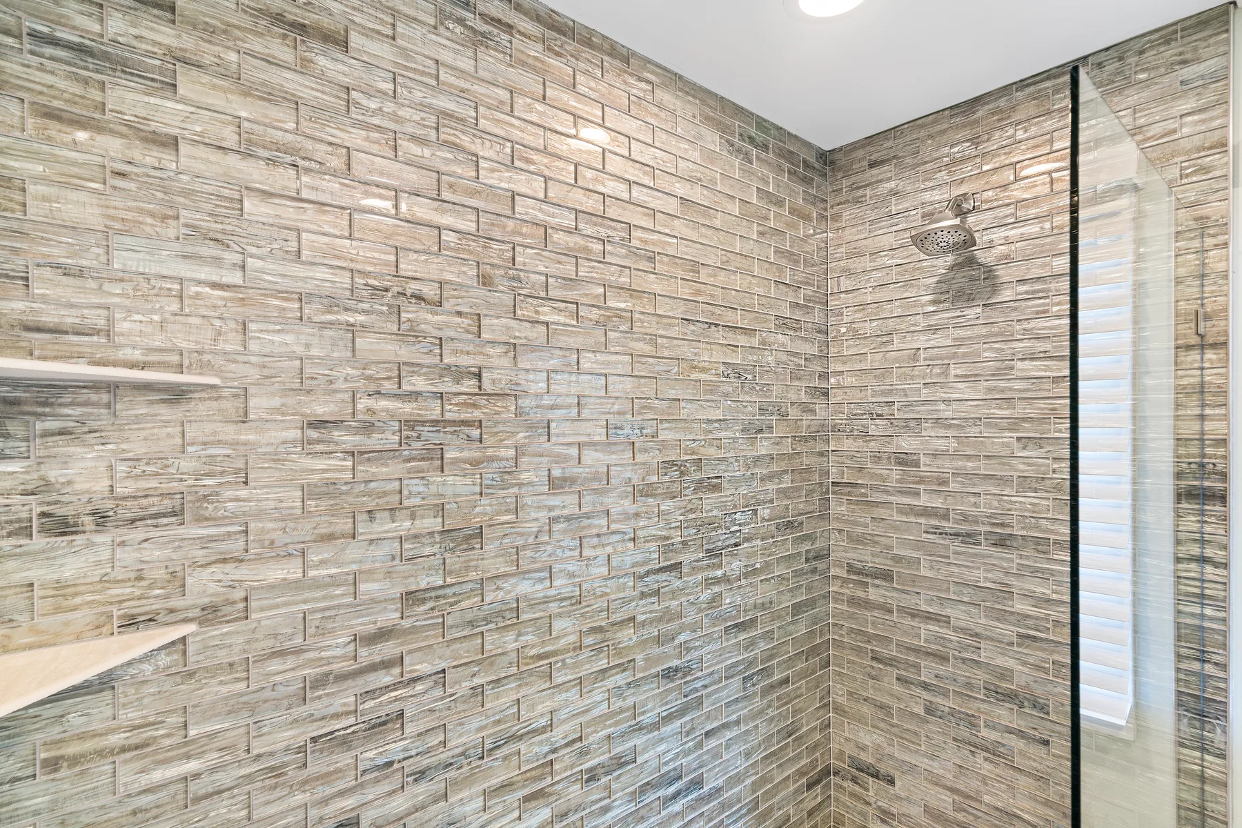 A tiled shower area with a glass panel and wall-mounted showerhead.