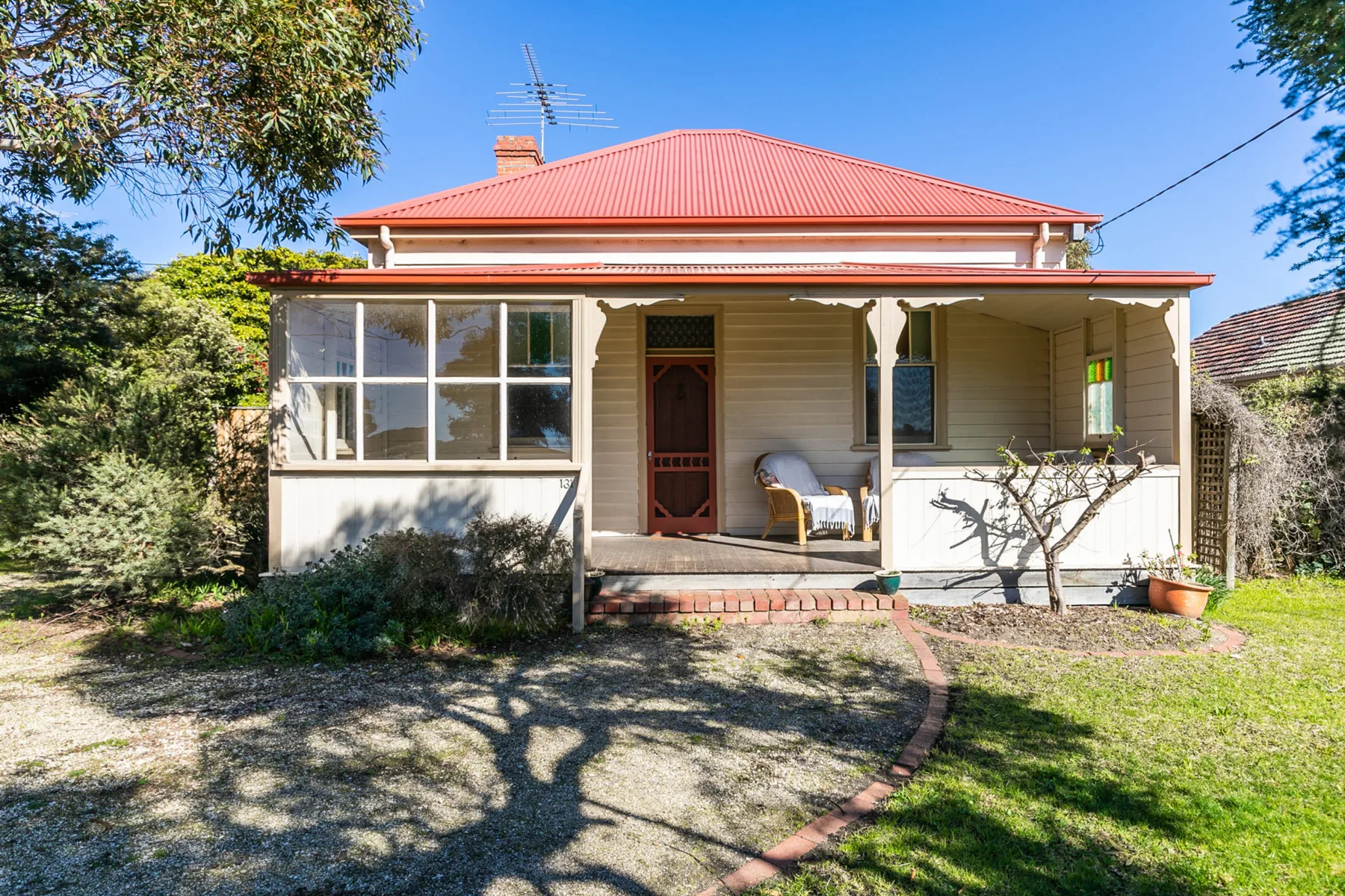 A cream-colored house with a red roof faces a small front garden.
