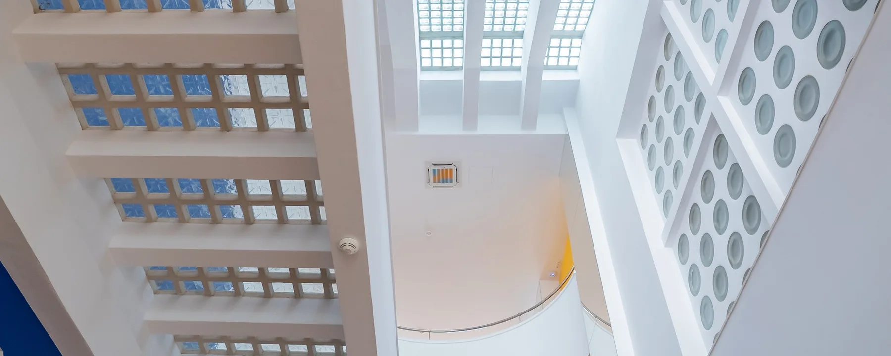 Espacio representativo del hotel: Un atrio interior visto desde abajo, con tragaluces y aberturas circulares en la pared.
