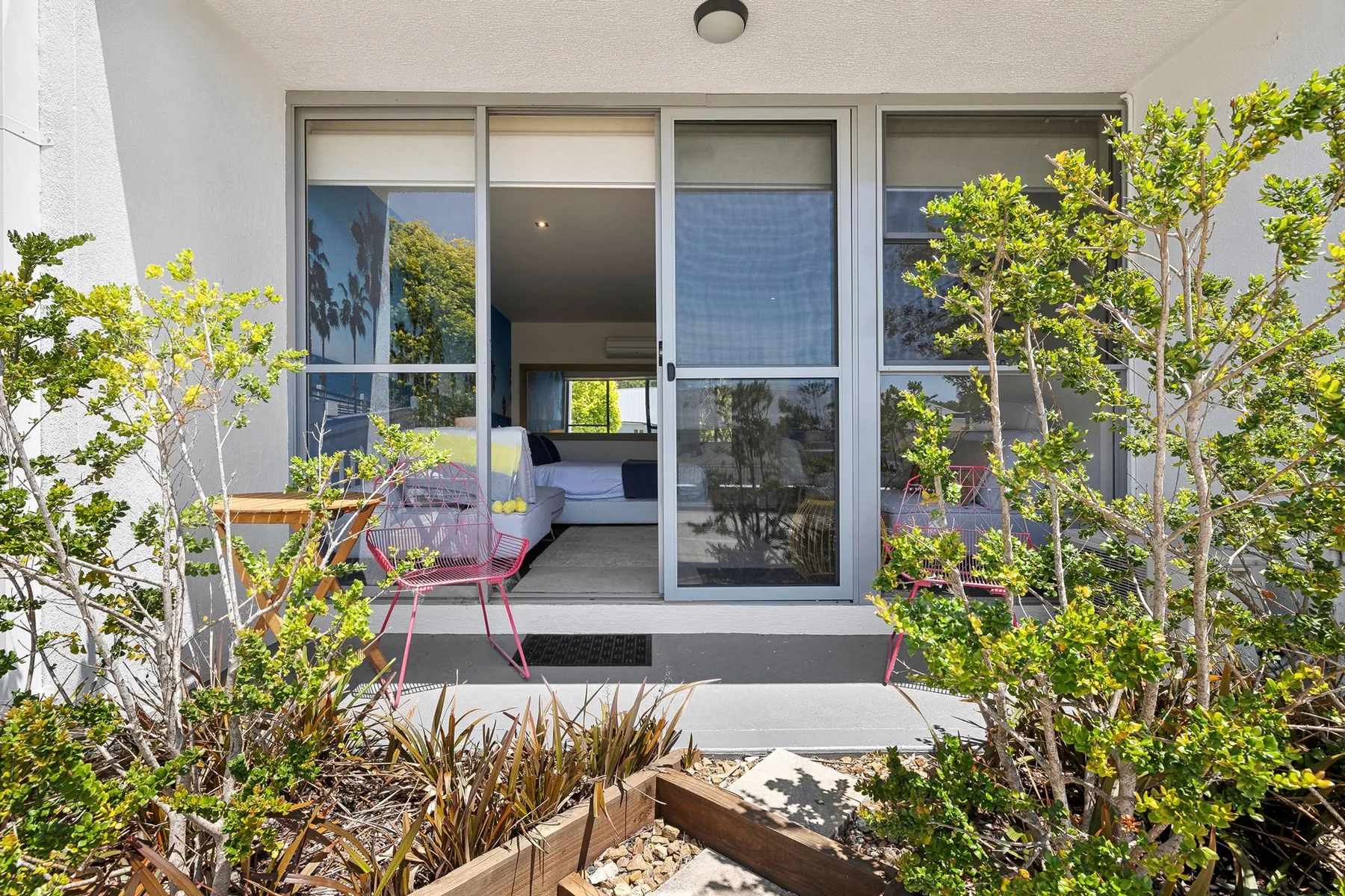 A patio entrance with a sliding glass door opens onto a bedroom.
