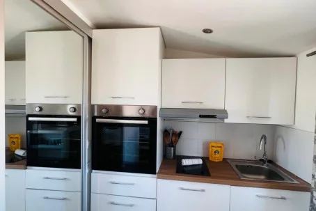 A modern kitchen with built-in ovens, white cabinets, and a sink.