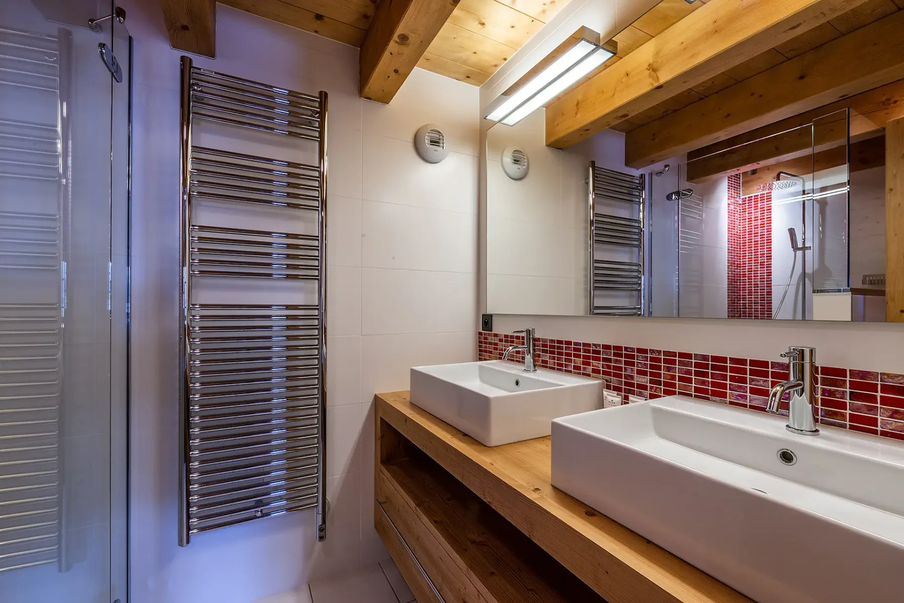 Un baño con dos lavabos blancos sobre una larga encimera de madera bajo un espejo.