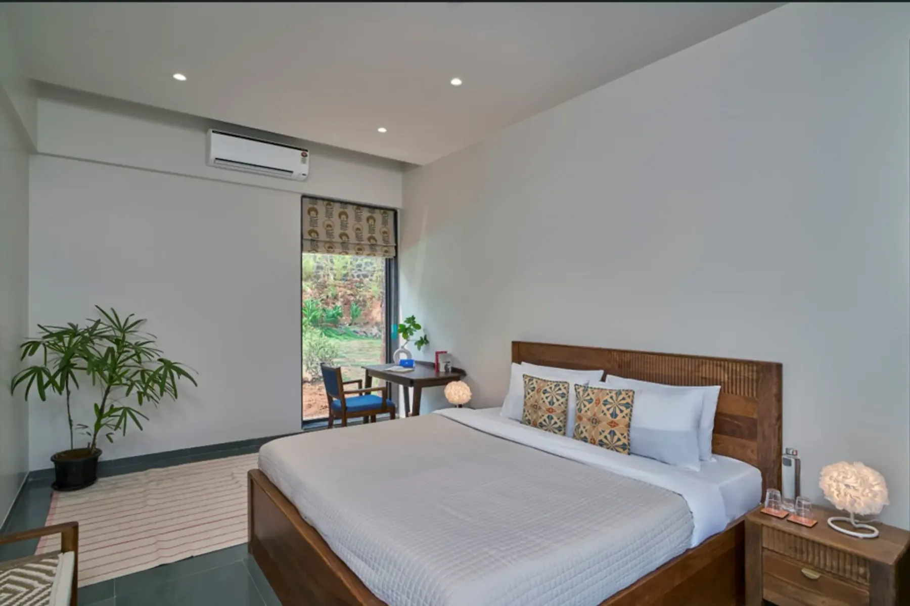 Un dormitorio con una cama de madera y una pequeña zona de estar junto a la ventana.